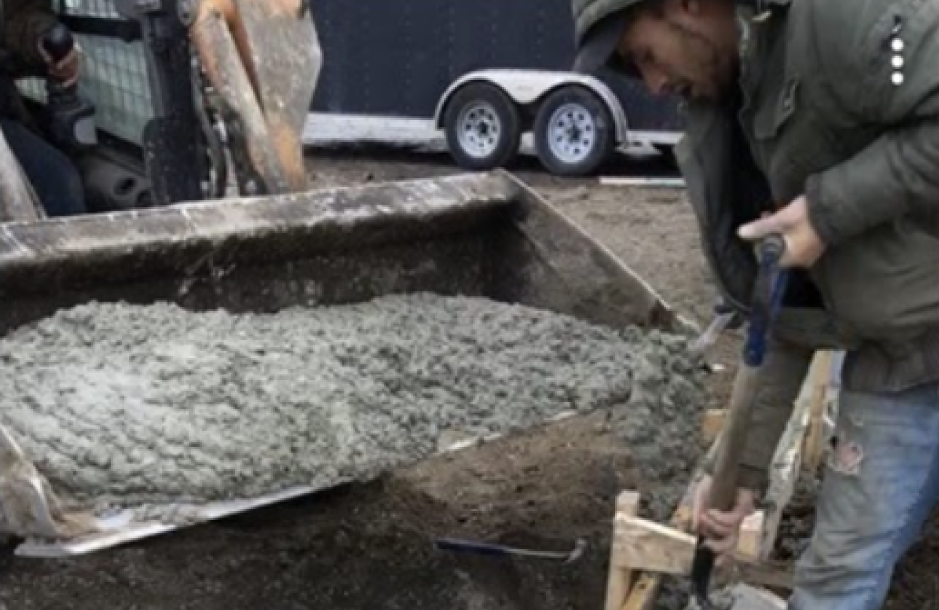 Seal Canada A person shoveling wet recycled asphalt from a tractor bucket into a wooden frame. Asphalt & Coatings